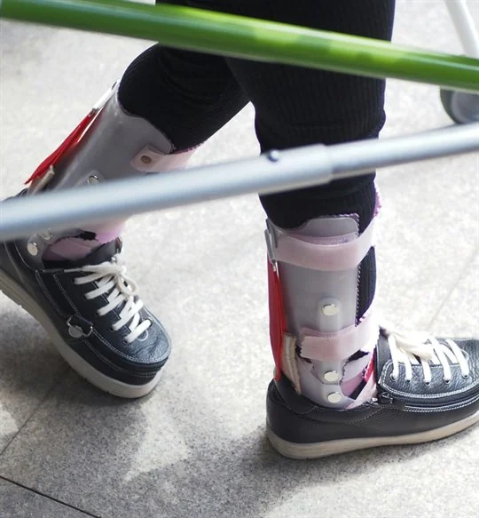 Child with ankle-foot orthoses using a walking frame
